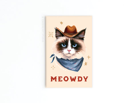 Add Western charm to your fridge with the Meowdy Cowboy Cat Refrigerator Magnet by Onderkast Studio—featuring a grumpy cat in a brown cowboy hat and blue bandana, MEOWDY in bold red, plus decorative stars on a beige background.