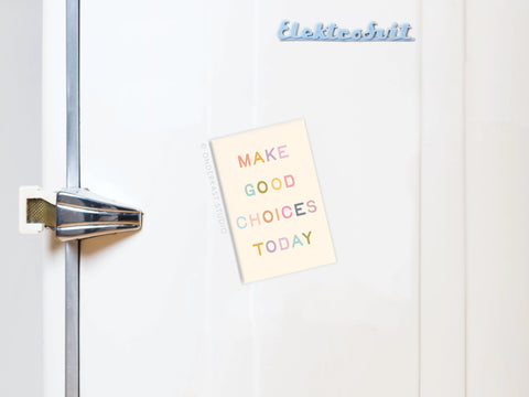 A white fridge with a silver handle and blue Elektrobit label displays the Onderkast Studio Make Good Choices Today Refrigerator Magnet, offering motivation to make wise decisions every time you grab a snack.