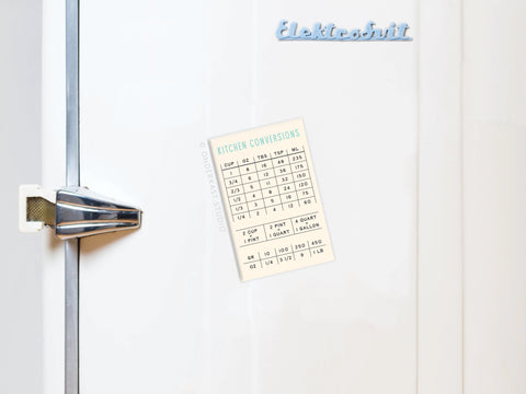 A white fridge with a vintage handle and Onderkast Studio label features the Kitchen Conversions Refrigerator Magnet, showing measurements for cups, tablespoons, teaspoons, milliliters, quarts, and ounces—ideal for cooking.