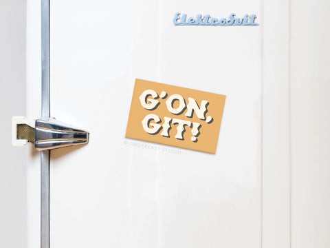 A refrigerator with a silver handle features the G’on Git Refrigerator Magnet by Onderkast Studio, displaying “GON, GIT!” in bold white letters on a tan background for rustic charm. The word Elektrobrüt is shown near the top in blue.