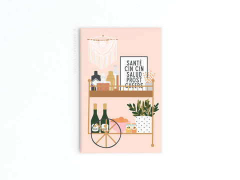 The Cheers Bar Cart Refrigerator Magnet by Onderkast Studio features a chic bar cart with bottles, glasses, plants, and art displaying toasts like Santé, Cin Cin, Salud, Prost, and Cheers on a light pink background—perfect for your fridge!.