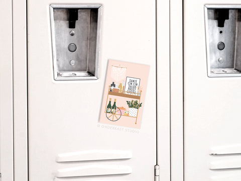 A white locker displays the Cheers Bar Cart Refrigerator Magnet by Onderkast Studio, showcasing chic illustrations of plants, wine bottles, and décor. The locker door features a metal handle and vents for added style.