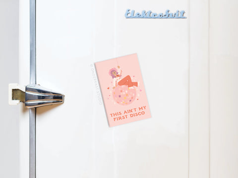 The Ain’t My First Disco Refrigerator Magnet by Onderkast Studio features vibrant pink art of a person with an afro on a disco ball and the text THIS AINT MY FIRST DISCO.