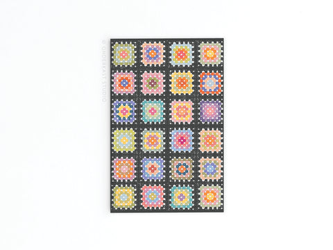 The Granny Squares Crochet Blanket Refrigerator Magnet by Onderkast Studio features a vibrant grid of square patterns inspired by crochet and quilts, capturing the handmade warmth of classic designs on a bold black background.