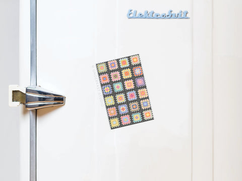 A white fridge with a retro handle features Onderkast Studio’s Granny Squares Crochet Blanket Refrigerator Magnet and a light blue “Elektrobrüt” magnet, bringing handmade charm to your kitchen decor.