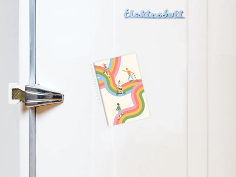 A vibrant postcard of kids playing on rainbow paths is held to a white fridge by the Waves of Happiness Refrigerator Magnet from Onderkast Studio. Elektrobrüt appears on the fridge, and a silver handle is visible on the left.