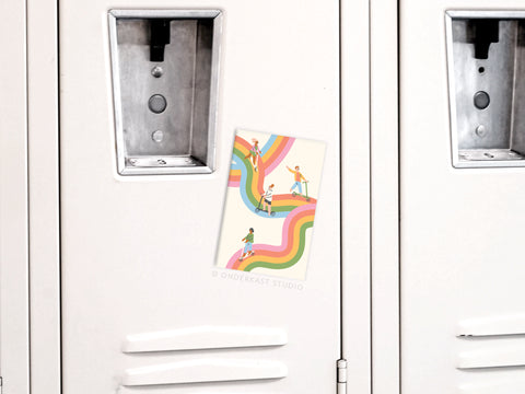 The Waves of Happiness Refrigerator Magnet by Onderkast Studio, featuring vibrant illustrations of people on curvy rainbow lines, is attached to a white locker door between two lockers.