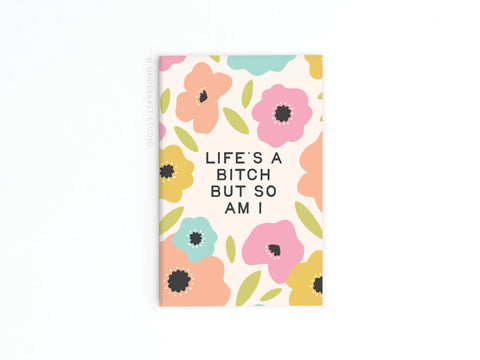 The Life’s a Bitch But So Am I Refrigerator Magnet by Onderkast Studio features bold, colorful flowers and leaves on white, with the empowering phrase LIFES A BITCH BUT SO AM I displayed at the center.
