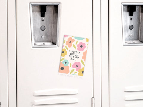 The “Life’s a Bitch But So Am I” refrigerator magnet by Onderkast Studio features pastel flowers on a cream background, delivering an empowering message and high-quality design—perfect for adding flair to any metal surface.