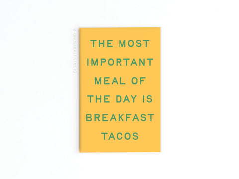 The Onderkast Studio Breakfast Tacos Refrigerator Magnet features a yellow card with green text: THE MOST IMPORTANT MEAL OF THE DAY IS BREAKFAST TACOS. Perfect quirky kitchen decor or a fun accent for your fridge, shown on a simple white background.