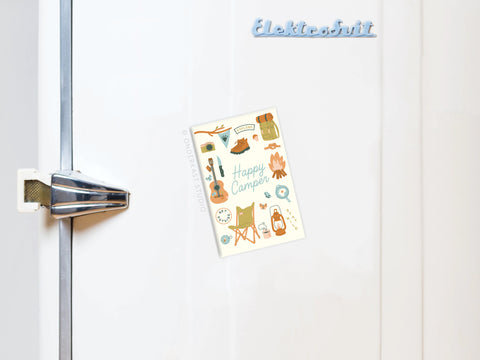 A white fridge with a silver handle features the Onderkast Studio Happy Camper Refrigerator Magnet, showing colorful camping illustrations like a tent, guitar, and campfire. The word Elektrobrüt appears at the top.