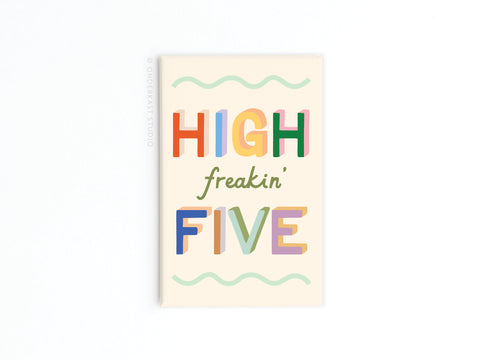 The High Freakin’ Five Refrigerator Magnet by Onderkast Studio features bold, vibrantly printed letters and green script on a cream background, with wavy green lines at the top and bottom.