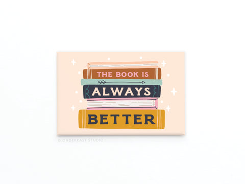 The Book Is Always Better Refrigerator Magnet by Onderkast Studio features three stacked books with the quote on their spines, set against a light peach background with sparkles—an ideal, charming gift for book lovers.