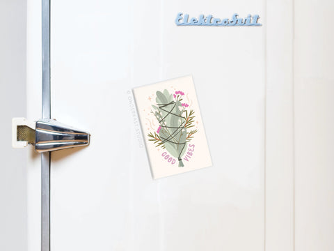 A white fridge with a silver handle displays a Good Vibes postcard featuring cactus art, held by the Onderkast Studio Good Vibes Smudge Stick Refrigerator Magnet, adding cheer to the scene.