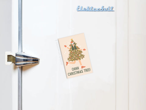 A white fridge with a metallic handle features the Onderkast Studio Ohh Christmas Tree Girl Refrigerator Magnet, vibrantly printed with a tree costume and OHHH CHRISTMAS TREE!—a festive holiday accent. The word Elektrobrikt appears in blue on the fridge.
