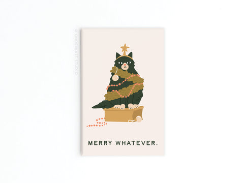 A grumpy black cat in a box, adorned with holiday garlands, beads, and a star topper, is featured on the Onderkast Studio Merry Whatever Cat Refrigerator Magnet. Below the cat, “MERRY WHATEVER” is written on a simple light background.