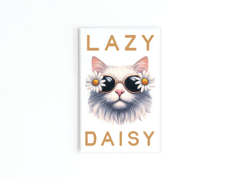 The Lazy Daisy Cat Refrigerator Magnet by Onderkast Studio features a fluffy white cat in daisy sunglasses with “LAZY DAISY” in bold tan letters—full of feline charm, perfect for adding personality to your fridge.