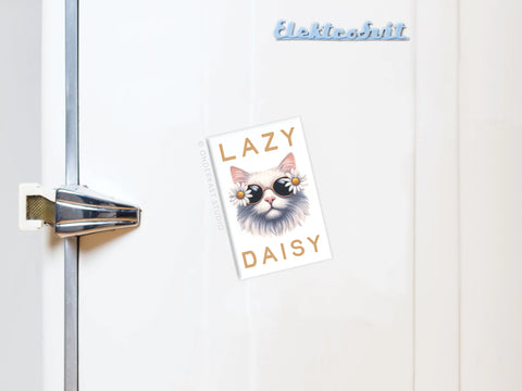 A white fridge with a metal handle displays the Onderkast Studio Lazy Daisy Cat Refrigerator Magnet—showing a cat in sunglasses and daisies with “LAZY DAISY.” The fridge’s brand “Elektrosvit” appears on top.