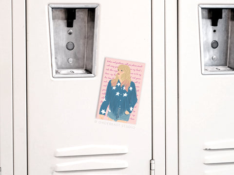 The TS Lover Refrigerator Magnet by Onderkast Studio features an illustrated blonde Swiftie in a blue star-patterned jacket with pink text, displayed on a white locker door.