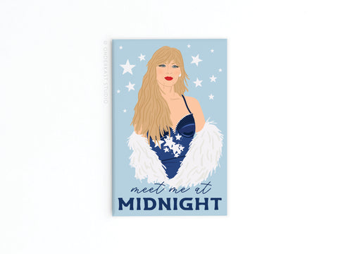 The TS Midnights Refrigerator Magnet by Onderkast Studio features a woman with long blonde hair in a blue dress and white feathered shawl, framed by celestial motifs and the phrase “meet me at MIDNIGHT”—ideal for poetic storytelling fans.