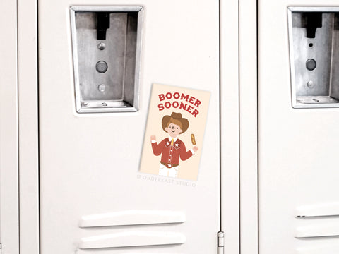 Show your Oklahoma Sooner pride with the Boomer Sooner Refrigerator Magnet by Onderkast Studio, featuring a cartoon cowboy in a red jacket holding up a finger and football—perfect for any fan’s fridge or locker.