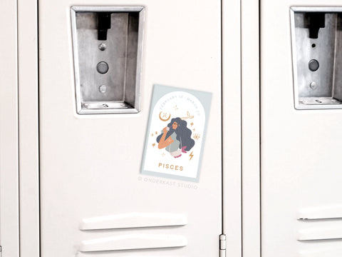 Add a celestial touch to your space with the Pisces Zodiac Refrigerator Magnet by Onderkast Studio, featuring a colorful illustration of a long-haired person, stars, moons, fish, and the dates “February 19 - March 20.”.