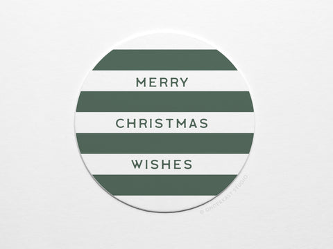 The Merry Christmas Wishes Coaster Set by Onderkast Studio features round pulp board coasters with white and dark green stripes, MERRY CHRISTMAS WISHES in all caps, and comes in recyclable packaging for eco-friendly gifting.