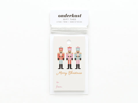 The Merry Christmas Nutcracker Gift Tag by Onderkast Studio features three illustrated nutcrackers on quality card stock, Merry Christmas text, labeled to/from spaces, and the brand name at the top.