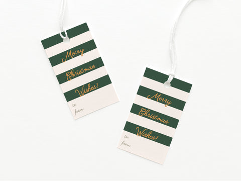 The Merry Christmas Wishes Stripe Gift Tag by Onderkast Studio features vibrant green and white stripes with gold Merry Christmas Wishes! text, spaces for to/from, and is attached to a white string.