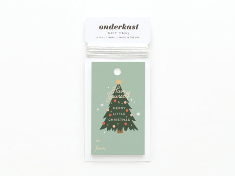 The Have Yourself a Merry Little Christmas Gift Tag by Onderkast Studio features a Christmas tree and festive message on green card stock. Printed in the USA, each tag comes with white twine and packaging labeled Onderkast Gift Tags.