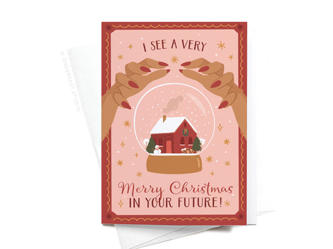 Send festive wishes with the I See a Very Merry Christmas In Your Future Folded Greeting Note Set of 10 by Onderkast Studio—featuring vibrant colors, sparkling details, and illustrated hands holding a snow globe on a pink and red background.