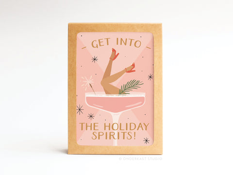The Get Into the Holiday Spirits! Cocktail Folded Greeting Note Set of 10 by Onderkast Studio features vibrant colors and a festive design with a cocktail glass holding a woman’s legs in red heels. Text: “Get into the holiday spirits!”.