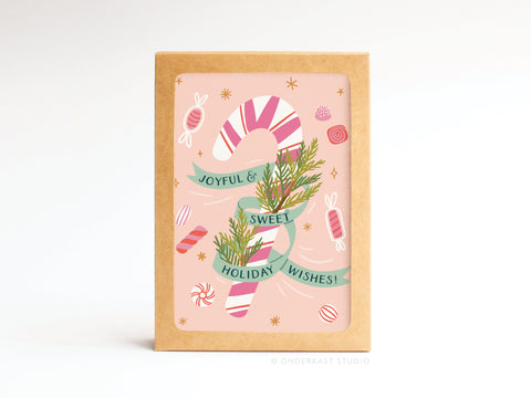 The Joyful & Sweet Holiday Wishes! Candy Cane Folded Greeting Note Set of 10 by Onderkast Studio features a pink and white candy cane with green ribbon, candies, and pine sprigs on premium card stock with a cheerful pink background. Printed in the USA.
