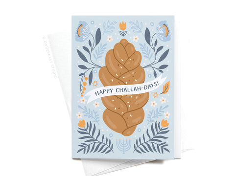 The Happy Challah-days! Folded Greeting Note Set of 10 by Onderkast Studio features challah bread with blue and orange florals, a white “Happy Challah-Days!” banner, and menorah. Printed in the USA on premium cardstock.