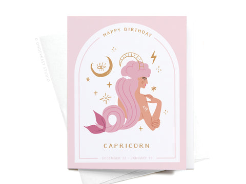The Happy Birthday Capricorn Zodiac Greeting Card by Onderkast Studio showcases a pink and gold design with an illustrated mermaid-like Capricorn, astrological icons, stars, and the message “Happy Birthday Capricorn,” listing December 22 – January 19.