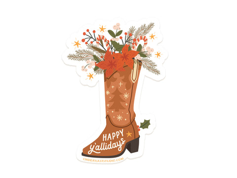The Happy Yallidays Cowboy Boot Sticker by Onderkast Studio features a brown boot with stars and “Happy Y’allidays,” filled with festive greenery, red flowers, berries, and a ribbon—printed on durable, water-resistant vinyl.