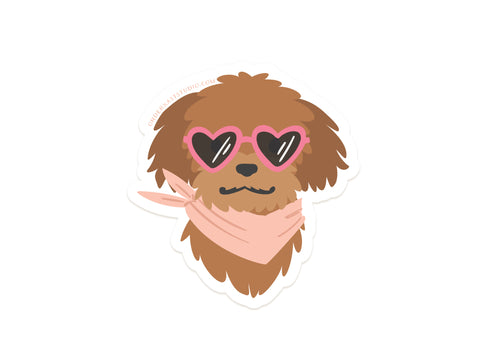 Dog w/ Heart Sunglasses Sticker by Onderkast Studio features a brown fluffy dog in pink heart-shaped sunglasses and a light pink bandana on a white background. This water resistant vinyl sticker is perfect for personalizing your items.