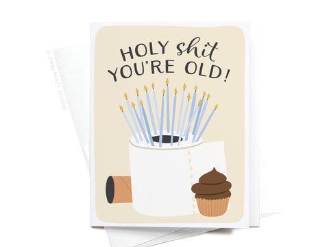 Celebrate with humor using the Onderkast Studio Holy Shit You’re Old! Greeting Card—featuring bold text, a toilet paper roll with candles, an empty roll, and a cupcake with a playful swirl design.